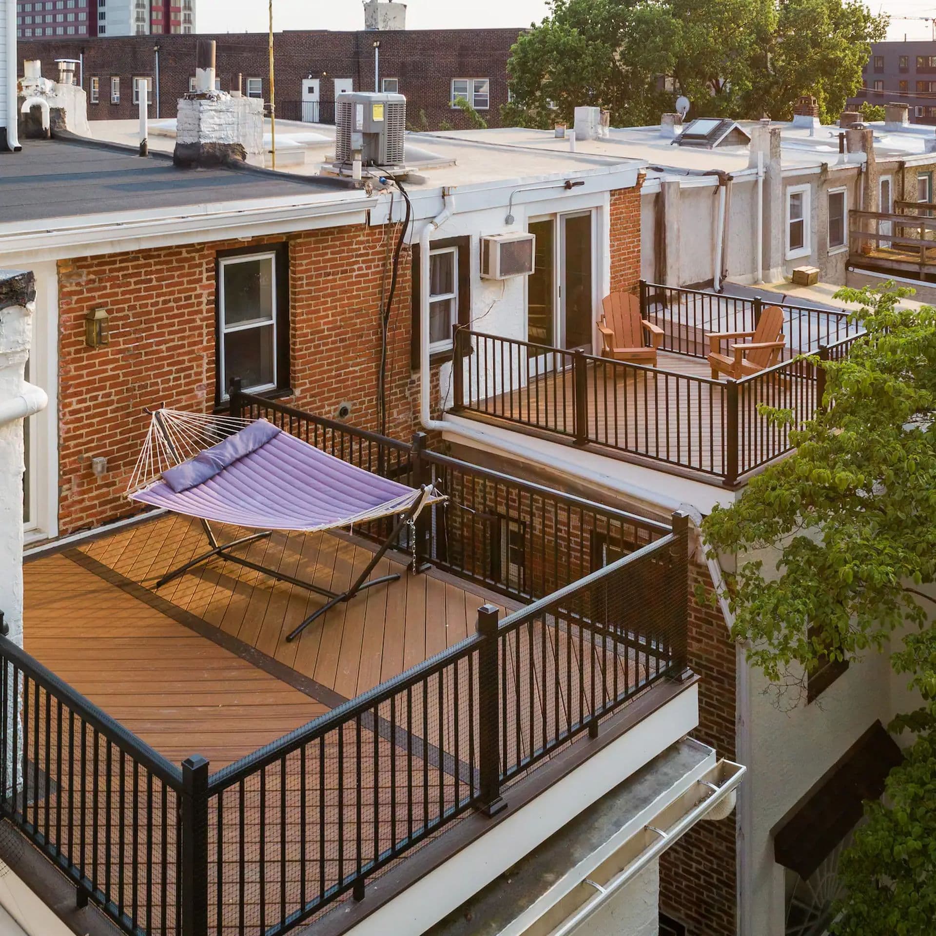 A rooftop deck with a hammock and a view of neighboring row houses.