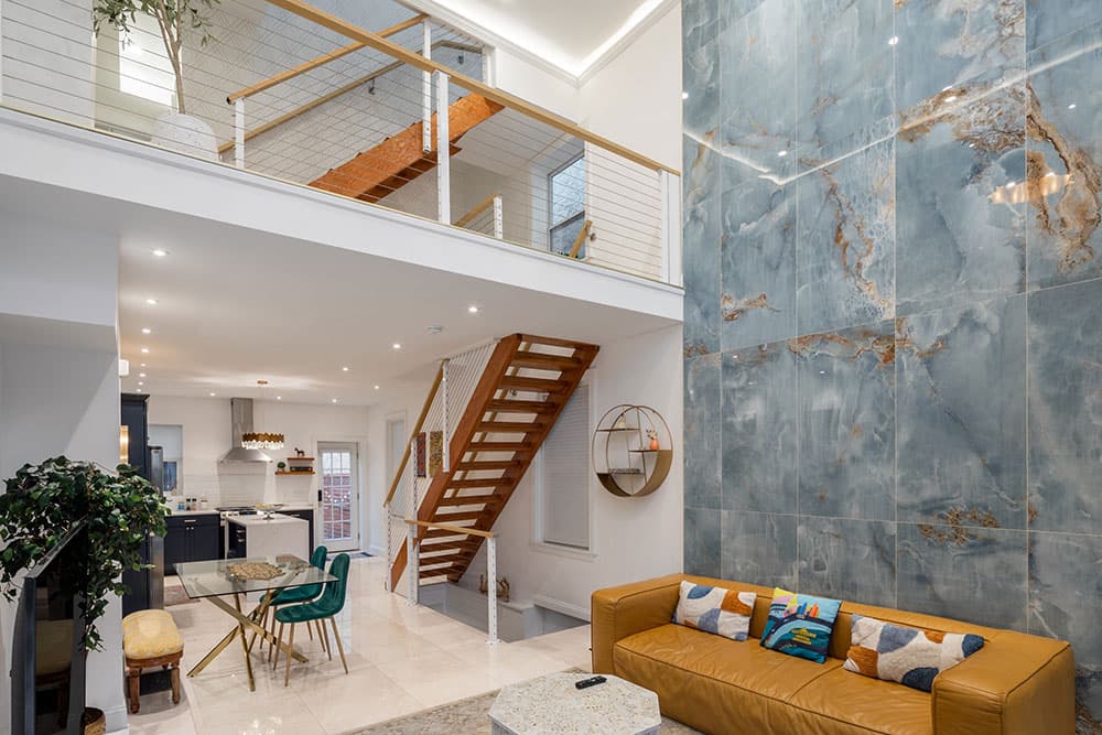 A modern living space featuring a staircase, a stylish couch, and a striking blue accent wall.