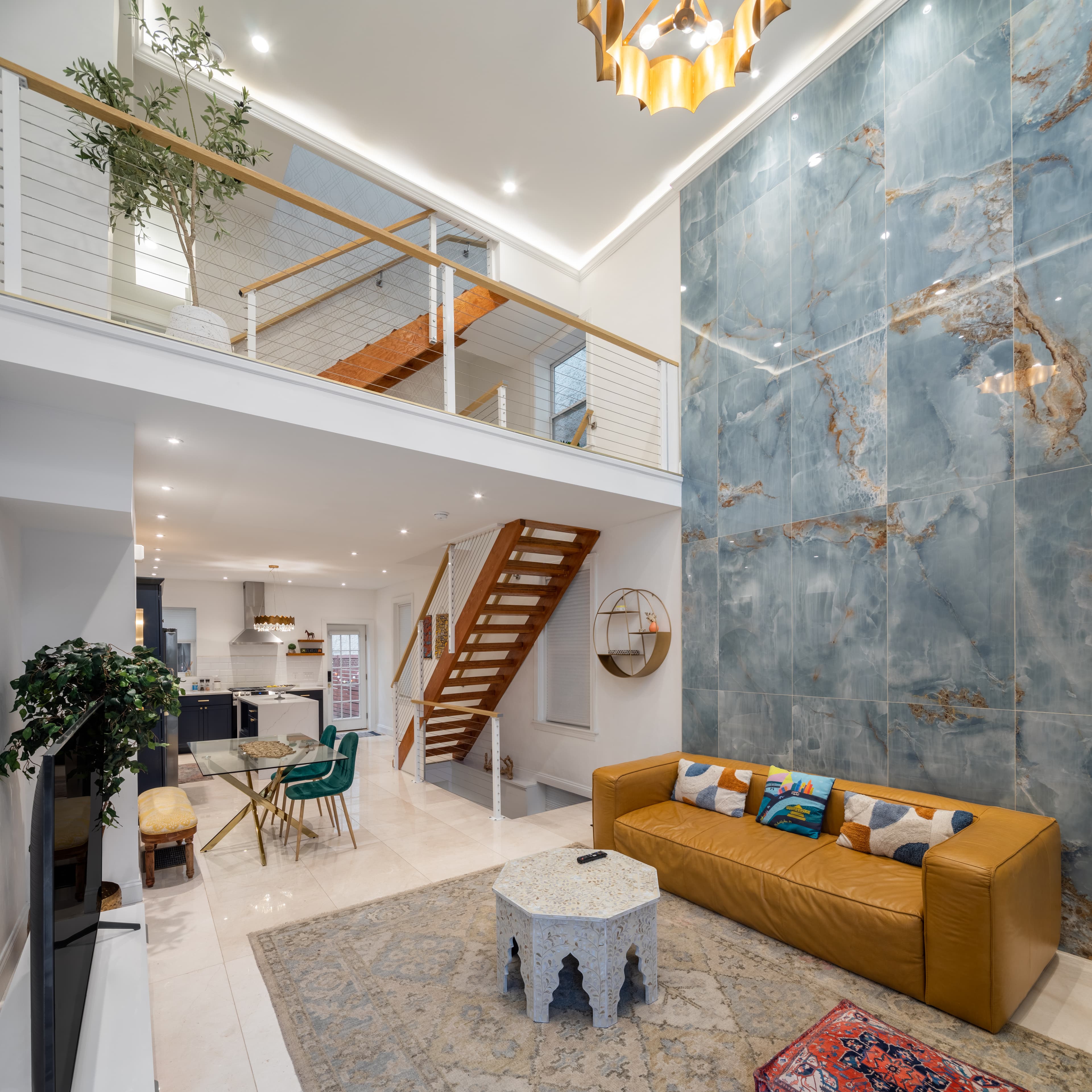 A modern, spacious living area featuring a tan sofa, decorative rug, and a striking blue accent wall.