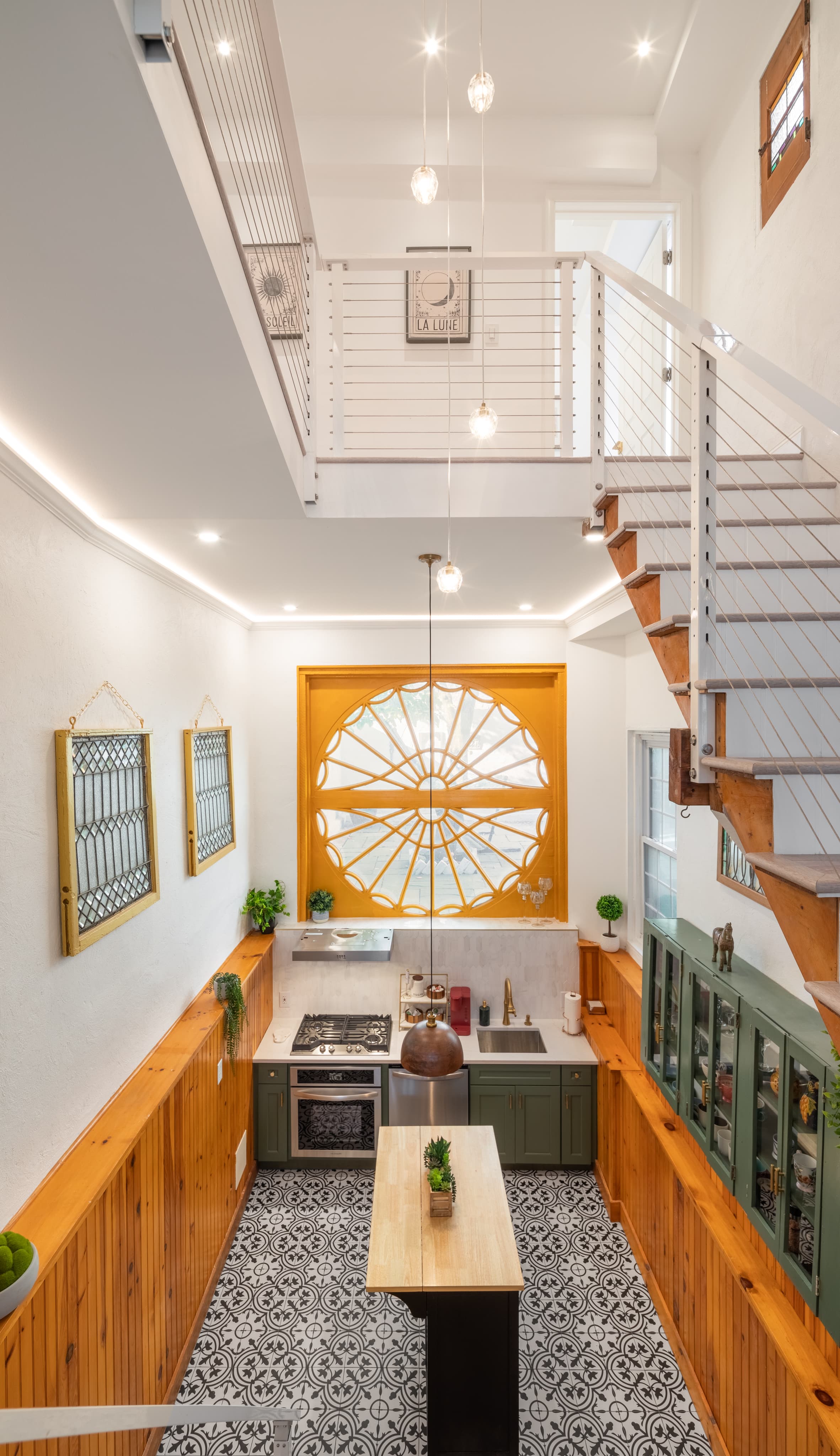 A bright, modern kitchen featuring a unique round window, wooden accents, and patterned flooring.